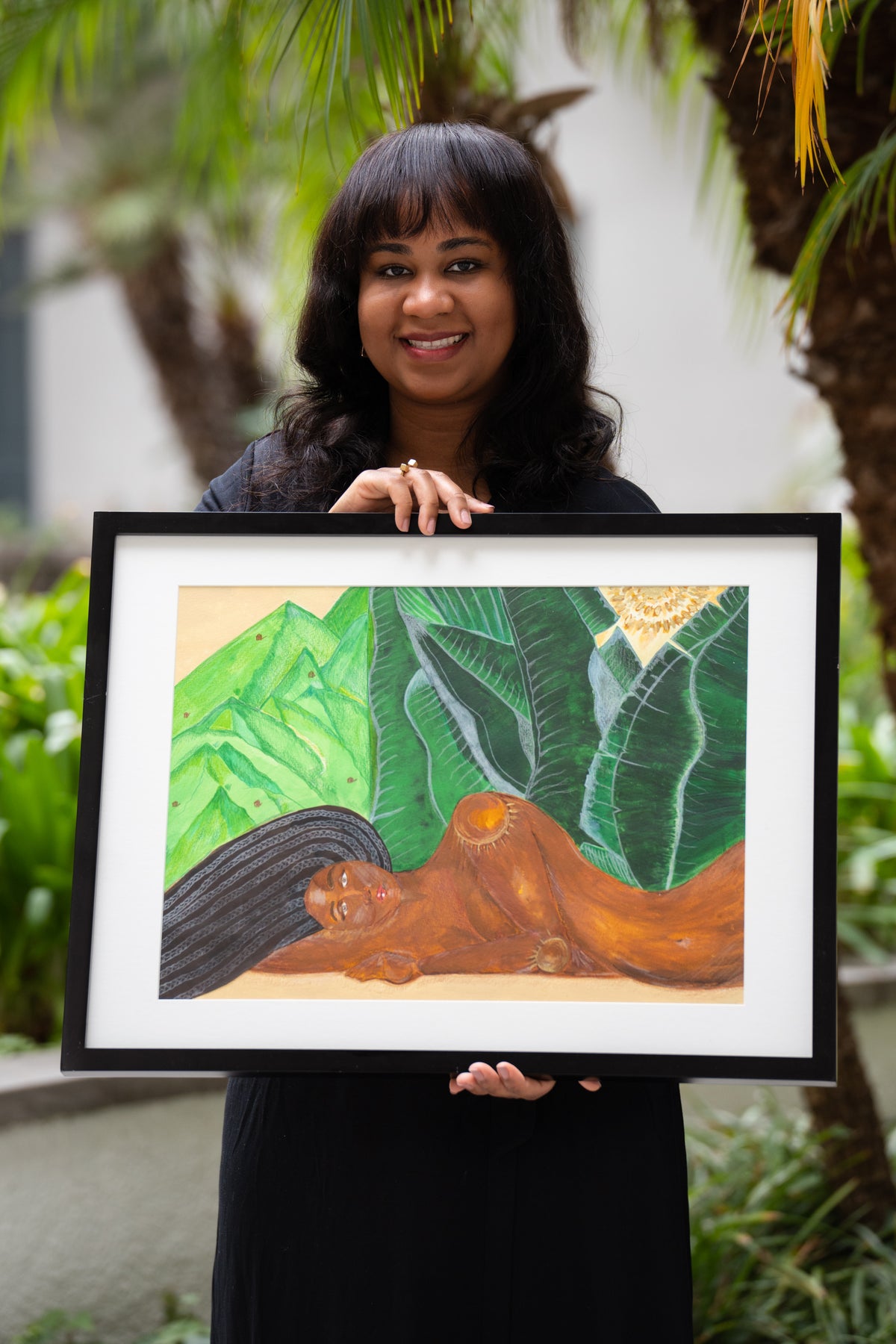 Artist Anya Cherrice holding And It's Beside Her That I Rest — original acrylic painting framed in black